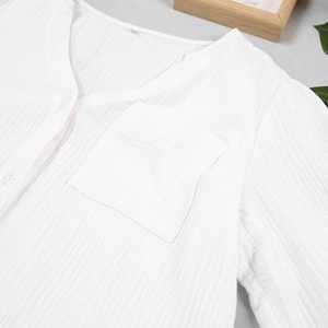 Detail of white cotton gauze pajama top with V-neckline, front pocket and textured fabric