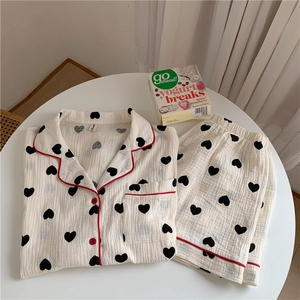 Detail of soft cotton gauze pajamas with heart print and red piping on a table