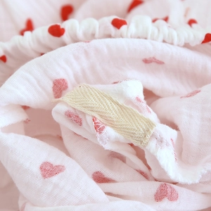 Detail of pink cotton crepe fabric with red heart prints and soft elastic waistband