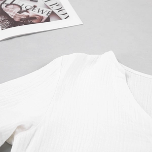 Detailed view of white V-neck pajamas with vertical wrinkle texture on cotton gauze fabric