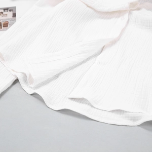 Detailed close-up of white wrinkled cotton texture and buttons on summer pajama set