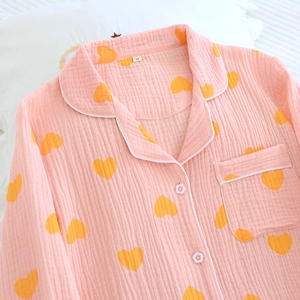 Détail du haut de pyjama rose à motifs cœurs avec boutons fleurs et liseré blanc