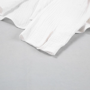 Close-up of white double-layered gauze sleeve cuff with button and muslin texture