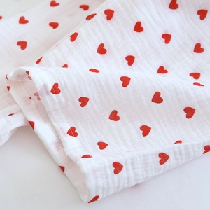Detail shot of breathable double gauze cotton fabric with small red heart prints