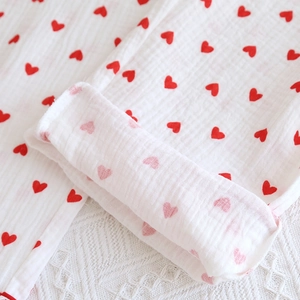Detail of red heart prints on white cotton gauze pajama pants with stitched hem finish
