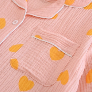Détail du haut de pyjama en gaze de coton rose avec motifs cœurs et boutons fleurs