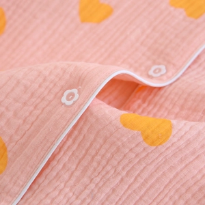 Gros plan sur tissu en coton gaufré à cœurs roses avec boutons fleurs et passepoil blanc