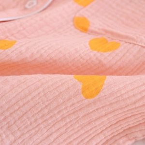Détail du pyjama en coton crépon rose avec imprimés cœurs jaunes et passepoil blanc