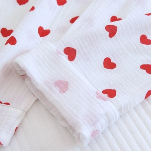 Détail de la manche d'un pyjama en coton blanc avec motifs cœurs rouges et texture de gaze