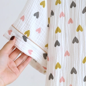Detailaufnahme von weichem Baumwoll-Crepe-Pyjama-Stoff mit bunten Herzmustern und Paspeln