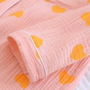 Détail du poignet du pyjama en crêpe rose à motif cœur avec liseré blanc et texture