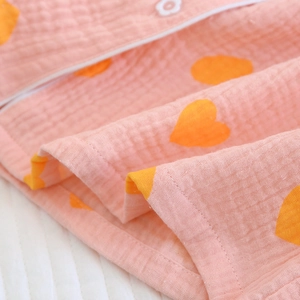 Gros plan détaillé du tissu crêpe rose avec cœurs orange et coutures soignées