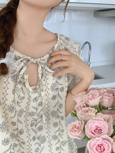 Detail of floral print sleepwear featuring tie-neck with drop hollow and lace trim