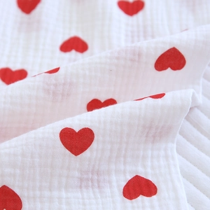Gros plan sur le tissu de pyjama en gaze de coton blanc avec des motifs de coeurs rouges