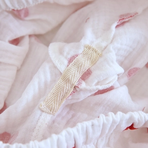 Détail du tissu en gaze de coton doux à pois rouges et couture renforcée de la taille élastique