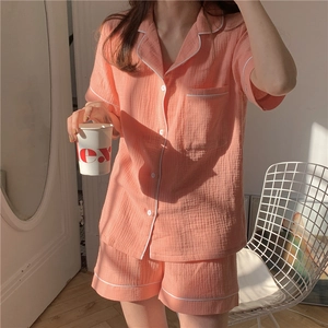 Detail of coral cotton gauze pajama set with white contrast piping and soft texture