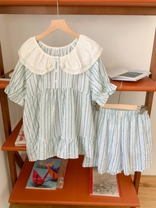 Détail d'un pyjama à rayures vertes avec grand col en dentelle sur un cintre