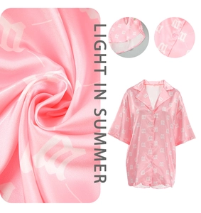 Detail of pink satin shirt featuring white letter print and soft silk-like texture