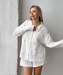 Gros plan d'imprimés cœurs roses sur pyjama en coton crème avec détails boutons et col