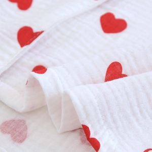 Détail du tissu en gaze de coton blanc avec motifs de cœurs rouges et coutures soignées
