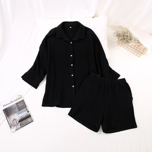 Flat lay detail of black crinkle gauze pajamas set with buttoned shirt and elastic shorts