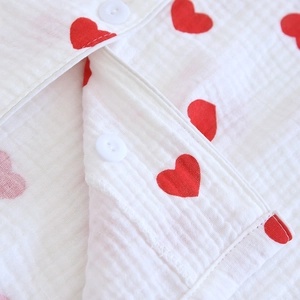 Détail de l'imprimé cœurs rouges sur gaze de coton blanc avec boutons ronds