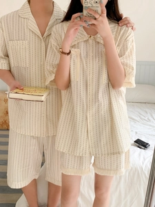 Detail of couple's striped summer pajamas featuring tassel hems and breathable fabric