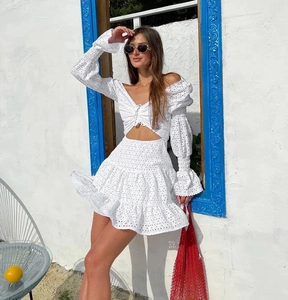 Dettaglio dell'abito in pizzo ricamato bianco con ritagli in vita e gonna a balze
