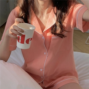 Detail of coral pink seersucker pajamas set with white piping and button closure