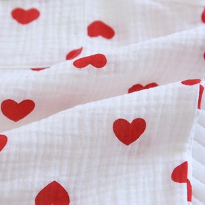 Détail du tissu en double gaze de coton doux avec imprimés coeurs rouges et texture