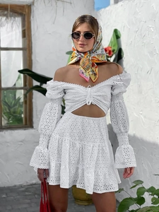 Dettaglio di un abito bianco con spalle scoperte, pizzo e vita con cut-out