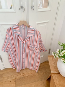 Détail du haut de pyjama à rayures et manches courtes avec poche sur une porte en bois