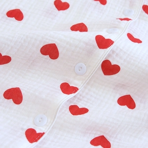 Détail du motif cœur rouge sur tissu de pyjama en coton double gaze avec bouton blanc