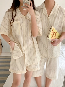 Detail of couple's cream pajamas featuring elegant tassel trim and vertical dot textures