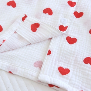 Détail d'un haut de pyjama en coton doux avec motifs de cœurs rouges et bouton blanc