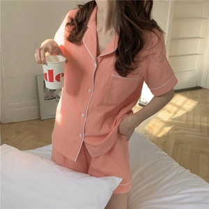 Detail of coral pink cotton gauze pajamas with white piping and short sleeve button-down top