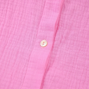 Macro shot of breathable pink crepe fabric texture with a pearly white button detail