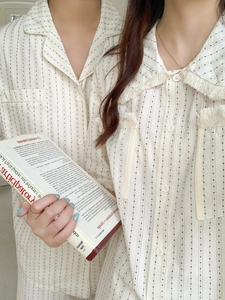 Detail of couple's cream pajamas featuring starry stripes and tassel collar texture
