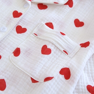 Détail de motifs de cœurs rouges sur pyjama en gaze de coton blanc avec poche et boutons