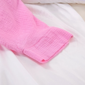 Detail view of pink cotton muslin fabric with crinkle texture and sleeve stitching detail