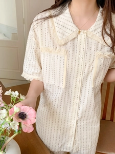 Close-up of beige short-sleeve pajama top with fringe details and dotted stripe pattern