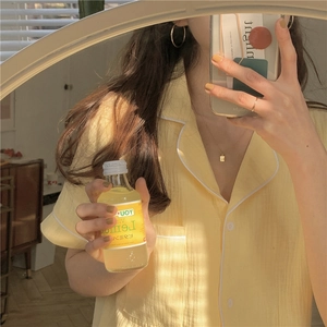 Detail of pale yellow short-sleeved pajama shirt with white piping and chest pocket