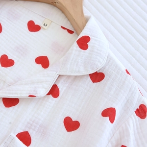 Gros plan d'un pyjama en gaze de coton à motif cœur avec un col Claudine sur cintre en bois