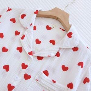 Détail d'un haut de pyjama en coton blanc avec des motifs de petits cœurs rouges