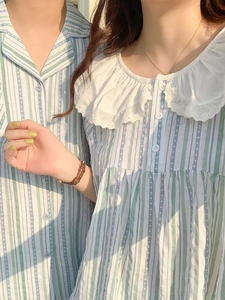 Détail de pyjama rayé vert avec col Claudine en dentelle blanche et boutons chic
