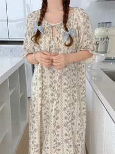Detail view of beige cotton pajama set with floral patterns and a blue lace bow decoration