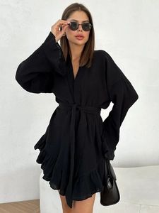 Detail of black cotton crepe wrap dress showing textured fabric and ruffled hemline