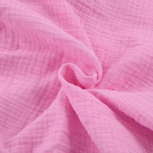 Detailed close-up of bright pink cotton crepe fabric with soft breathable wrinkled texture