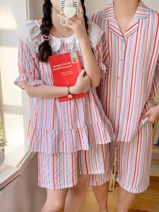 Détail de pyjama rayé rouge et bleu avec col de poupée en dentelle et fermeture boutonnée