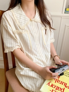 Detail view of beige pajama top with fringe-trimmed collar and vertical dot stripes